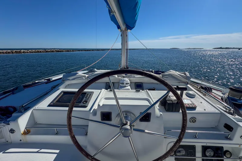 Slide: The Image of Helm of 2005 Lagoon 440 catamaran sailing on open water under clear blue sky. - 3