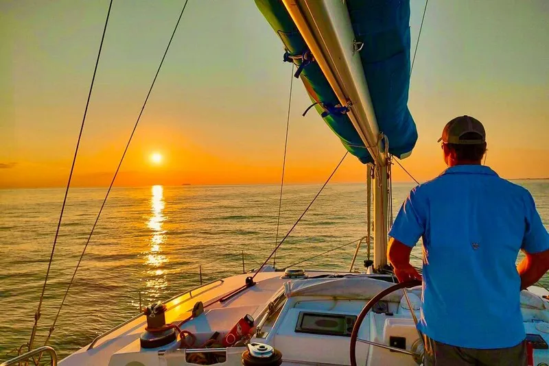 Slide: The Image of Man steering Lagoon 440 catamaran at sunset, 2005 model, serene ocean view. - 51