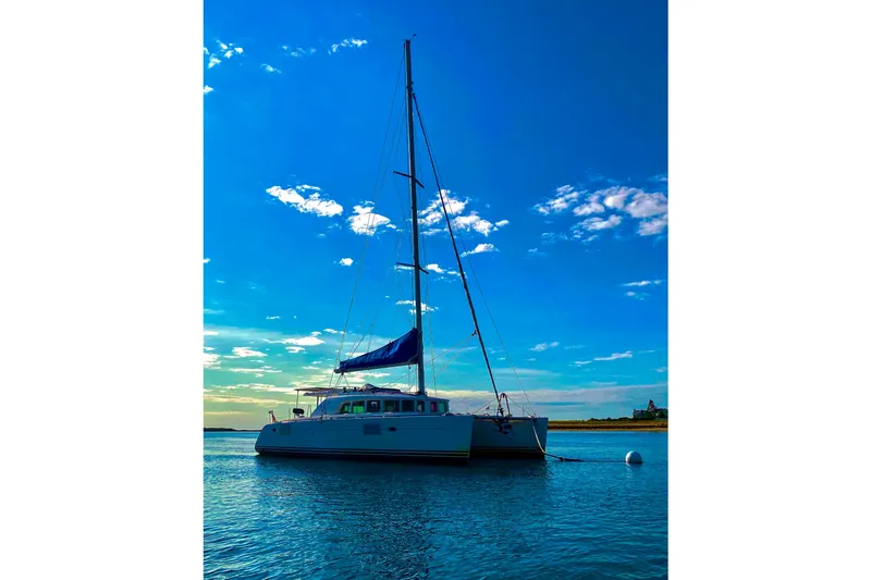Slide: The Image of 2005 Lagoon 440 catamaran anchored on calm water under a clear blue sky. - 53