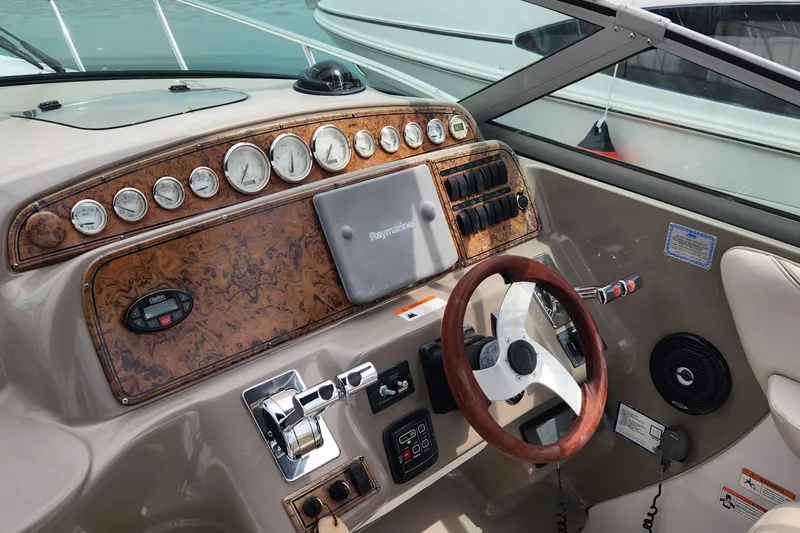 Slide: The Image of 2006 Larson 3700 Cabrio boat dashboard with wood accents and steering wheel. - 2