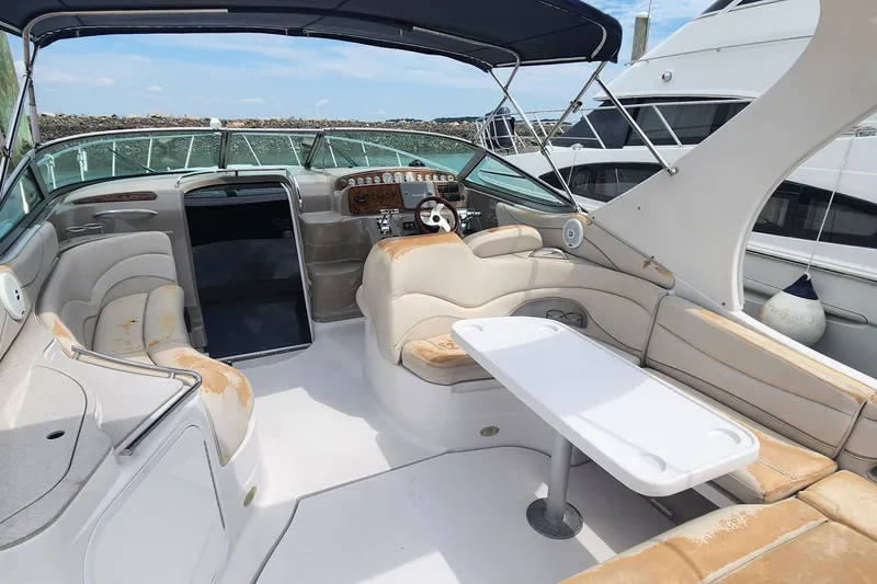 Slide: The Image of 2006 Larson 3700 Cabrio boat interior with seating, table, and helm, docked by the water. - 4