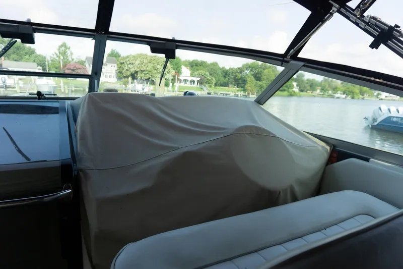Slide: The Image of Interior view of a 1993 Sea Ray 400 Express Cruiser with covered dashboard, overlooking a serene lake. - 15