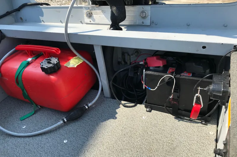 Slide: The Image of 2013 Lund 1600 Fury Tiller boat interior with red fuel tank and battery setup. - 16