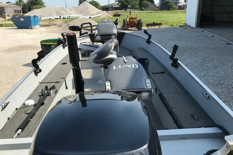 Slide: The Image of 2013 Lund 1600 Fury Tiller boat interior with seats and equipment, parked outdoors. - 6