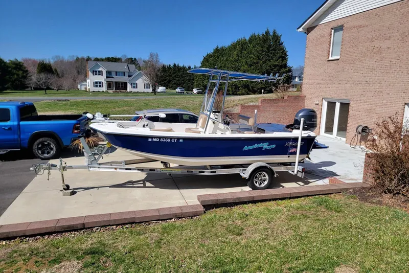 Slide: The Image of 2022 Sundance 20DX boat on trailer, parked in driveway beside brick house. - 3