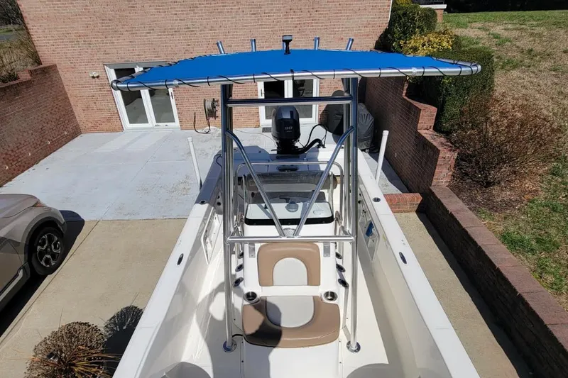 Slide: The Image of 2022 Sundance 20DX boat with blue canopy, parked in a driveway. - 7