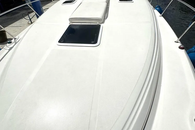 Slide: The Image of 2000 Sea Ray 340 Sundancer boat deck with hatches and railing, docked by water. - 6