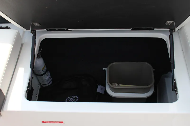 Slide: The Image of Open storage compartment in 2025 Cobalt R4 Surf boat, containing a fire extinguisher and accessories. - 14
