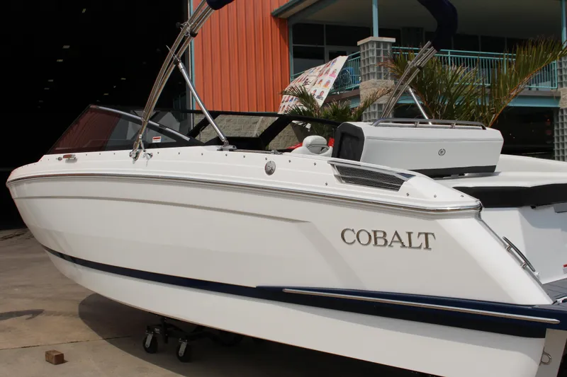 Slide: The Image of 2025 Cobalt R4 Surf boat in a marina, showcasing sleek design and modern features. - 3