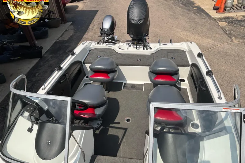 Slide: The Image of 2007 Ranger 1760 Angler boat interior with seating and motor, parked on pavement. - 5