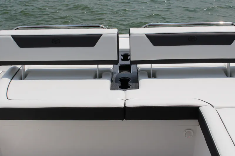 Slide: The Image of 2025 Cobalt R31 Surf boat with sleek white seating and cup holders on a calm water backdrop. - 12