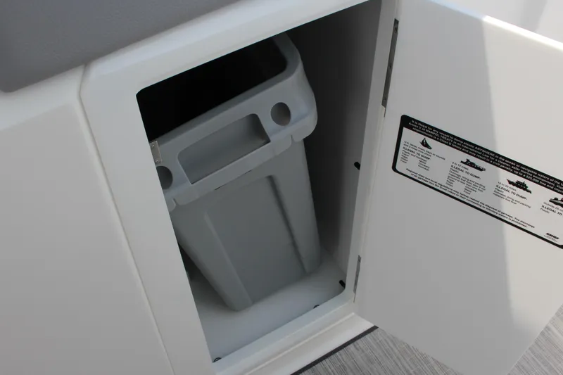 Slide: The Image of Storage compartment in 2025 Cobalt R31 Surf boat with waste bin and safety instructions. - 24