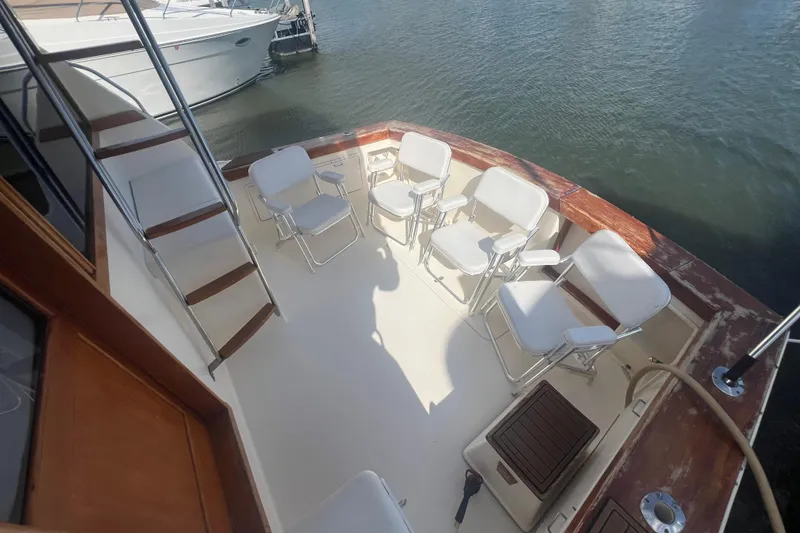 Slide: The Image of 1990 Ocean Yachts 35 Sport Sedan deck with white chairs and wooden accents. - 5