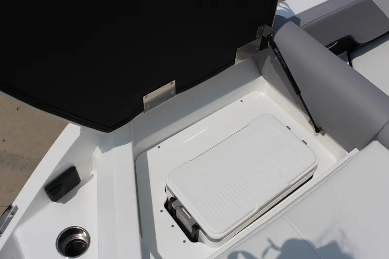Slide: The Image of 2025 Cobalt CS23 boat storage compartment with white cooler and seating area. - 22