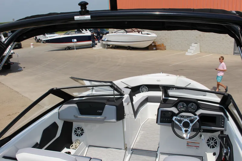 Slide: The Image of 2025 Cobalt CS23 boat interior with steering wheel, dashboard, and seating at a marina. - 48