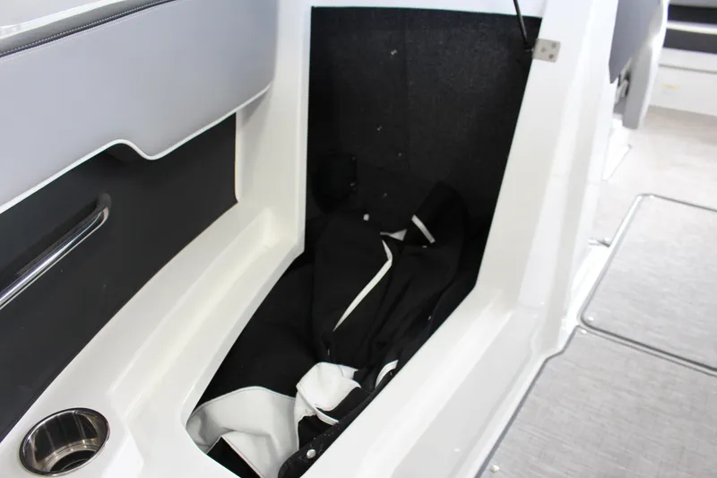 Slide: The Image of 2025 Cobalt CS23 Surf boat interior storage compartment with black and white fabric. - 11