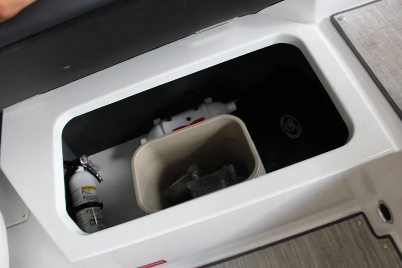 Slide: The Image of Storage compartment in 2025 Cobalt CS23 Surf boat with fire extinguisher and container. - 17