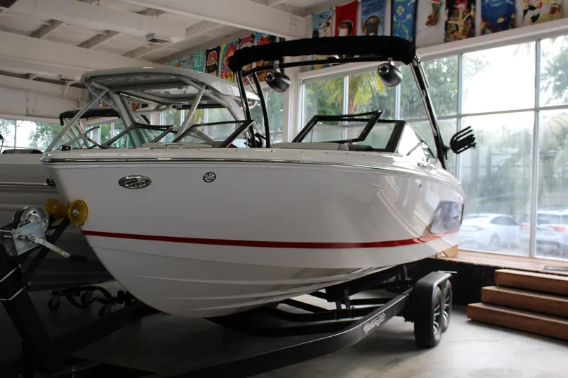 Slide: The Image of 2025 Cobalt CS23 Surf boat displayed indoors on a trailer. - 19
