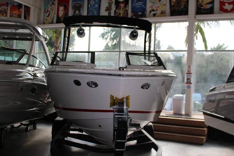 Slide: The Image of 2025 Cobalt CS23 Surf boat displayed indoors, surrounded by other boats. - 20