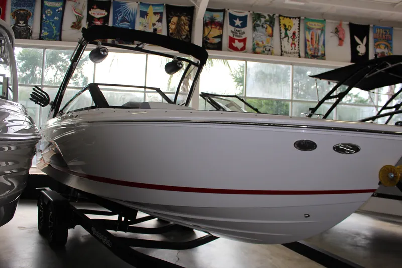 Slide: The Image of 2025 Cobalt CS23 Surf boat displayed indoors with vibrant banners above. - 21