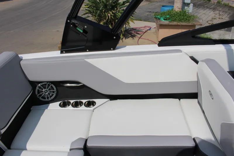 Slide: The Image of 2025 Cobalt CS23 boat interior with white seating, cup holders, and speaker. - 23