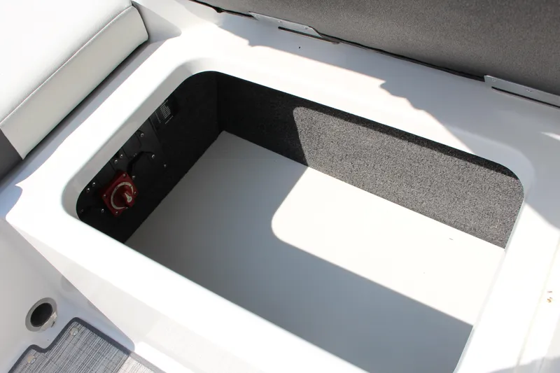 Slide: The Image of 2025 Cobalt CS23 boat storage compartment with red switch, gray interior. - 26