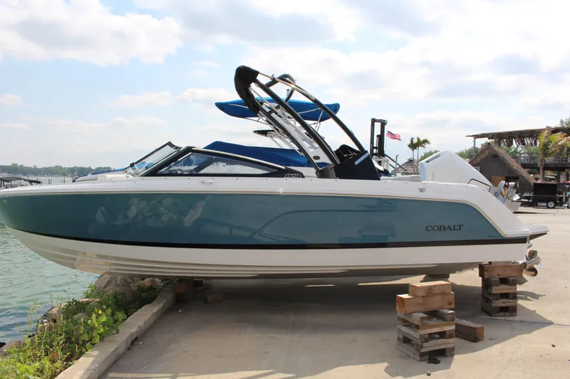 Slide: The Image of 2025 Cobalt CS23 boat on dock, blue and white design, sunny day. - 36
