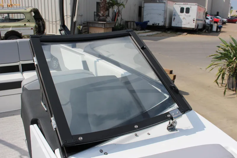 Slide: The Image of 2025 Cobalt CS23 boat windshield and seating area in a dockside setting. - 8