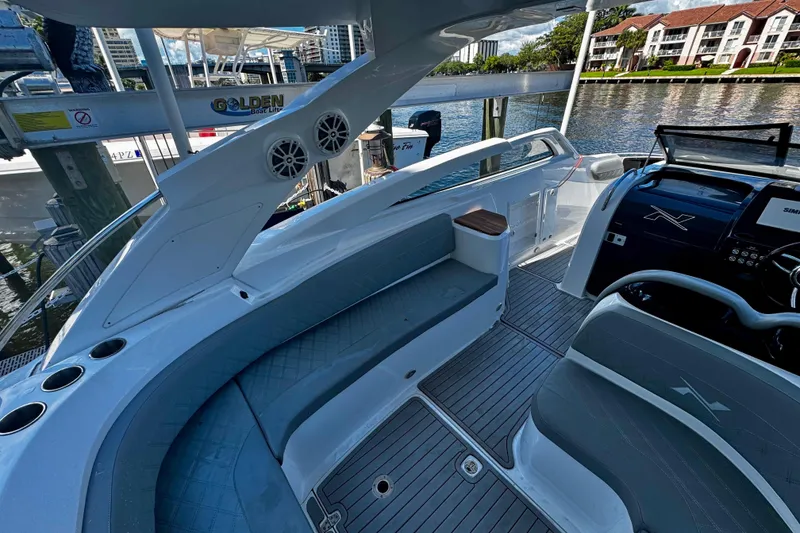 Slide: The Image of 2024 NX Boats NX 280 interior with seating, speakers, and control panel by the water. - 12