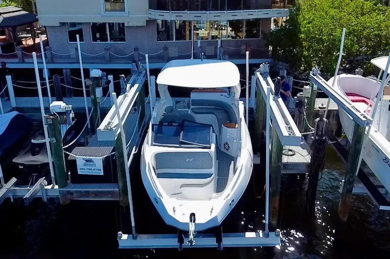 Slide: The Image of 2024 NX Boats NX 280 docked at marina with modern building backdrop. - 2