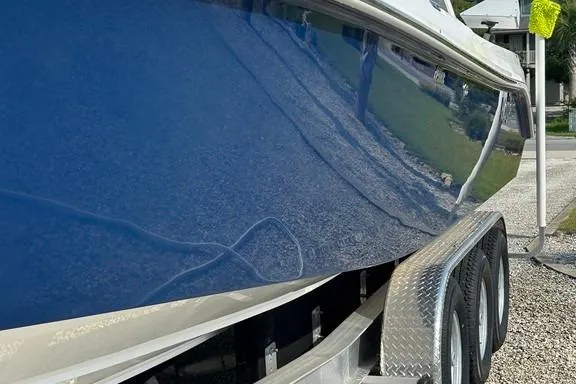 Slide: The Image of 2008 Everglades 290 CC boat on trailer, blue hull, parked on gravel. - 11