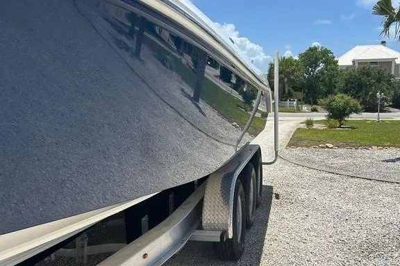 Slide: The Image of 2008 Everglades 290 CC boat on trailer, parked on gravel driveway under clear blue sky. - 5