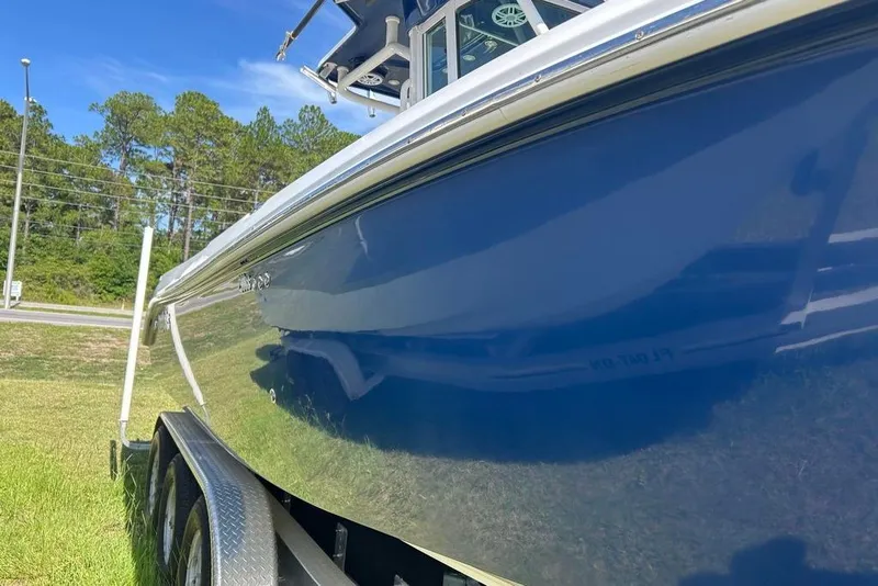 Slide: The Image of 2008 Everglades 290 CC boat on trailer, glossy blue hull, parked on grass. - 7