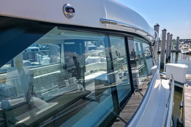 Slide: The Image of 2026 Regal 38 Grande Coupe yacht docked at marina, reflecting surrounding boats and clear sky. - 17