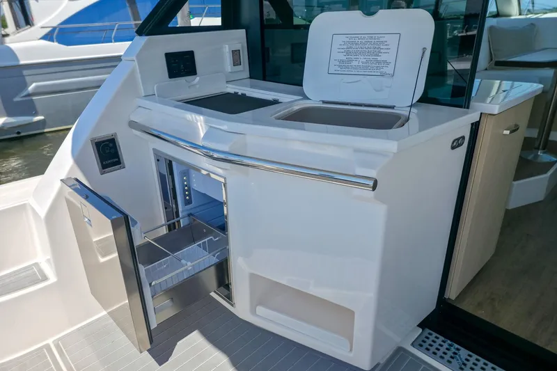 Slide: The Image of 2026 Regal 38 Grande Coupe yacht kitchenette with open fridge and sink. - 9