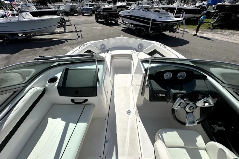 Slide: The Image of 2016 Yamaha Boats AR190 interior with steering wheel and seating, parked among other boats. - 16
