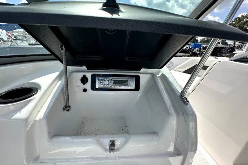 Slide: The Image of 2016 Yamaha AR190 boat storage compartment with stereo system, open lid, and cup holder. - 33
