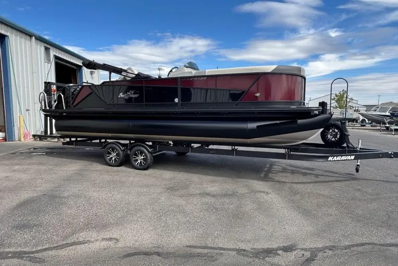 The Image of 2025 SunChaser Eclipse 23 Fish pontoon boat on trailer, parked outside a warehouse. - 1