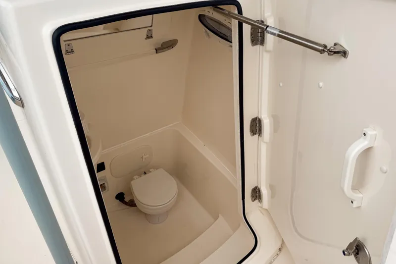 Slide: The Image of 2018 Cobia 261 Center Console boat interior with compact marine toilet. - 11