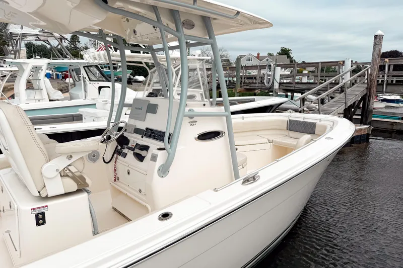 Slide: The Image of 2018 Cobia 261 Center Console boat docked at marina, featuring helm and seating area. - 13