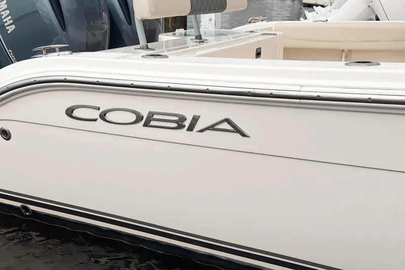 Slide: The Image of 2018 Cobia 261 Center Console boat, white exterior, docked near water. - 3