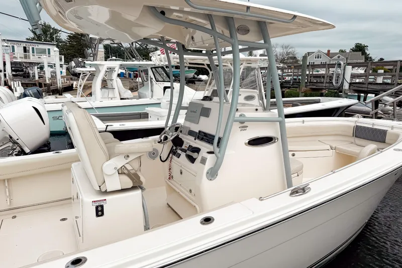 Slide: The Image of 2018 Cobia 261 Center Console boat docked at marina, featuring spacious seating and modern controls. - 6