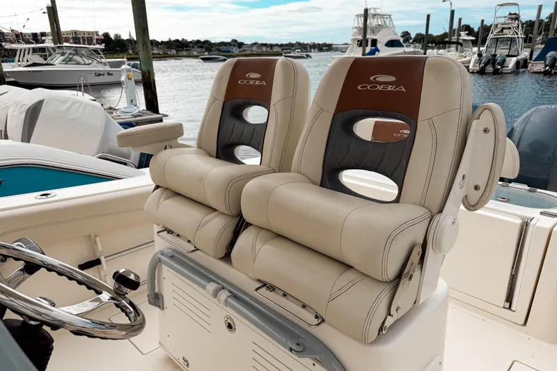 Slide: The Image of 2018 Cobia 261 Center Console boat seats at marina, featuring comfortable design and branding. - 8