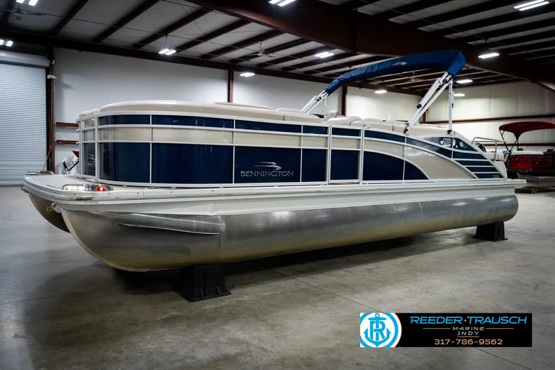 The Image of 2016 Bennington 2375 RSB pontoon boat in showroom, featuring blue and white design. - 2