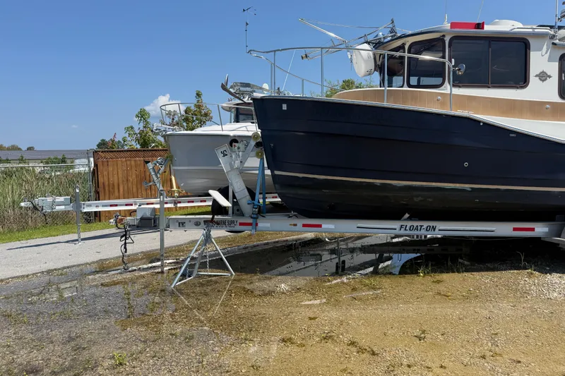 Slide: The Image of 2013 Ranger Tugs R27 Classic boat on trailer, parked outdoors under clear blue sky. - 2