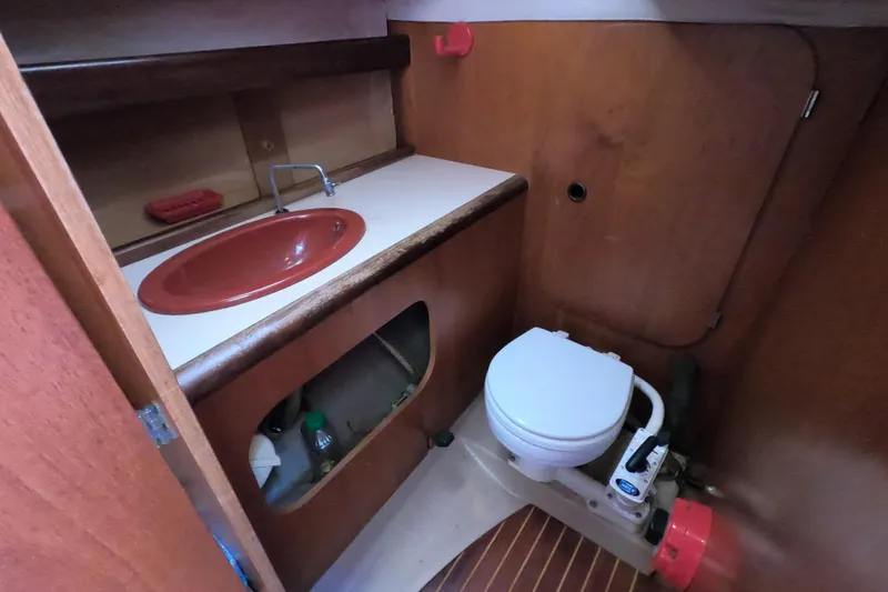 Slide: The Image of 1985 Beneteau First 29 yacht bathroom with red sink and compact toilet. - 10