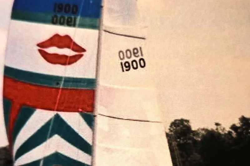 Slide: The Image of Sailboat with colorful sails featuring lips design, Beneteau First 29, 1985 model. - 7