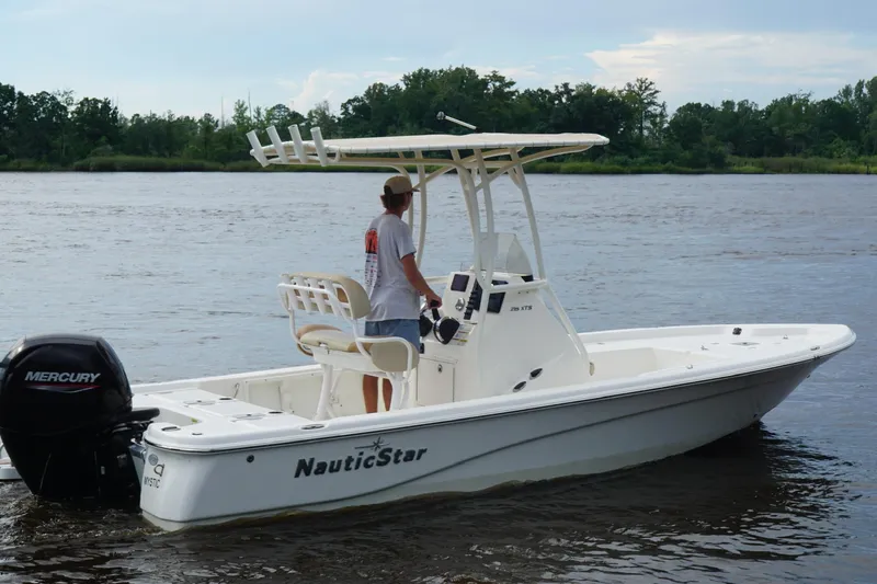 Slide: The Image of 2023 NauticStar 215XTS boat on a calm river, featuring a Mercury outboard motor. - 3