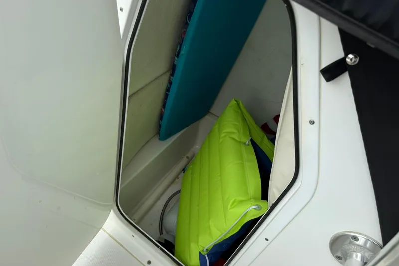 Slide: The Image of Storage compartment in 2013 Sea Hunt Triton 210 boat with colorful cushions. - 16