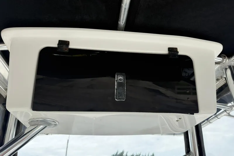 Slide: The Image of 2013 Sea Hunt Triton 210 boat storage compartment with black door and metal hinges. - 9